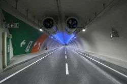 Długi czasy dojazdów to już przeszłość, przynajmniej dla wielu mieszkańców Stambułu. W związku z otwarciem nowego tunelu euroazjatyckiego, dotychczasowy czas podróży skrócił się ze 110 do 15 minut.    Najbardziej zaawansowany technologicznie tunel podmorski łączący europejską i azjatycką część Stambułu, znajduje się na głębokości prawie 107 metrów pod poziomem morza. Bosch odgrywa kluczową rolę w przedsięwzięciu, jako dostawca kompleksowego systemu zabezpieczeń, składającego się z systemu dozoru wizyjnego, systemu sygnalizacji pożaru i systemu kontroli dostępu. Wszystkie systemy są zintegrowane w ramach Building Integration System (BIS).   Zgodnie z przewidywaniami przez tunel ma przejeżdżać codziennie 120 000 pojazdów, a bezpieczeństwo użytkowników jest priorytetem dla operatorów. Ruch samochodów o tak ogromnym natężeniu jest przez całą dobę analizowany przez automatyczny system wykrywania wypadków bazujący na kamerach. Jego najważniejszym elementem jest system dozoru wizyjnego Bosch obejmujący inteligentną kombinację kamer sieciowych, co ma na celu spełnienie zmiennych wymagań w obrębie całej instalacji. Dla przykładu kamera FLEXIDOME IP 7000 VR jest wykorzystywana w obszarach, w których spodziewane jest pogorszenie sytuacji na drodze – kamera wyróżnia się wysoką odpornością na trudne warunki pogodowe oraz akty wandalizmu. W obszarach słabo oświetlonych sprawdzi się sieciowa kamera stałopozycyjna DINION IP starlight 8000 MP, która zapewnia szczegółowe odwzorowanie kolorów w warunkach, w których inne kamery musiałyby się już przełączyć na tryb monochromatyczny. Poza możliwością rejestrowania ważnych szczegółów, kamera znacząco poprawia bezpieczeństwo dzięki systemowi analizy wideo uwzględniającemu filtrowanie kolorów w scenach o minimalnym poziomie światła. W sytuacjach, gdy konieczne jest śledzenie, lokalizowanie i powiększenie wybranych obiektów, dobrym wyborem jest sieciowa kamera zmiennopozycyjna AUTODOME IP 5000 HD, stanowiąca uzupełnienie dla sieciowych kamer stałopozycyjnych DINION IP 7000 HD, które także zapewniają doskonałą jakość obrazu w jakości HD. Wbudowana funkcja analizy wideo w wybranych kamerach wspiera operatorów, szybko i automatycznie wykrywając niepożądane zdarzenia i umożliwiając bezzwłoczne wysłanie ekip ratowniczych i precyzyjne prowadzenie ich do celu.   Dwupoziomowa konstrukcja jezdni umożliwia samochodom szybki przejazd przez tunel. Rozwiązanie dostarczone przez firmę Bosch obejmuje także system kontroli dostępu, który monitoruje tunel w ponad 40 punktach, na całej jego długości, czyli ponad 5 kilometrach.   Centrala sygnalizacji pożaru Bosch Modular Fire Panel 5000 Series z 5 500 urządzeń peryferyjnych, na które składają się automatyczne czujki, sygnalizatory akustyczne i optyczne, jak również ręczne ostrzegacze pożarowe, pomaga w szybkim wykrywaniu pożarów. Ponad 100 telefonów alarmowych rozmieszczonych co 50 metrów oraz drzwi ewakuacyjne w tunelu zapewniają podróżującym dodatkowe bezpieczeństwo.