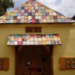 Zagrzeb -  mały, żółty domek z dachem, stworzonym z kilkudziesięciu różnych dachówek z kolorowymi wzorami. Fot. Kamila Ocimek. Braas, Superdekarz