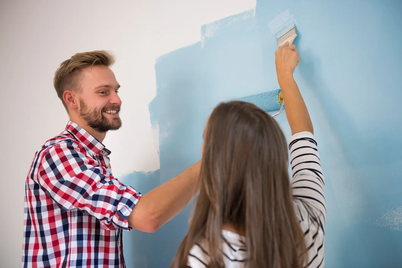 young couple painting blue wall