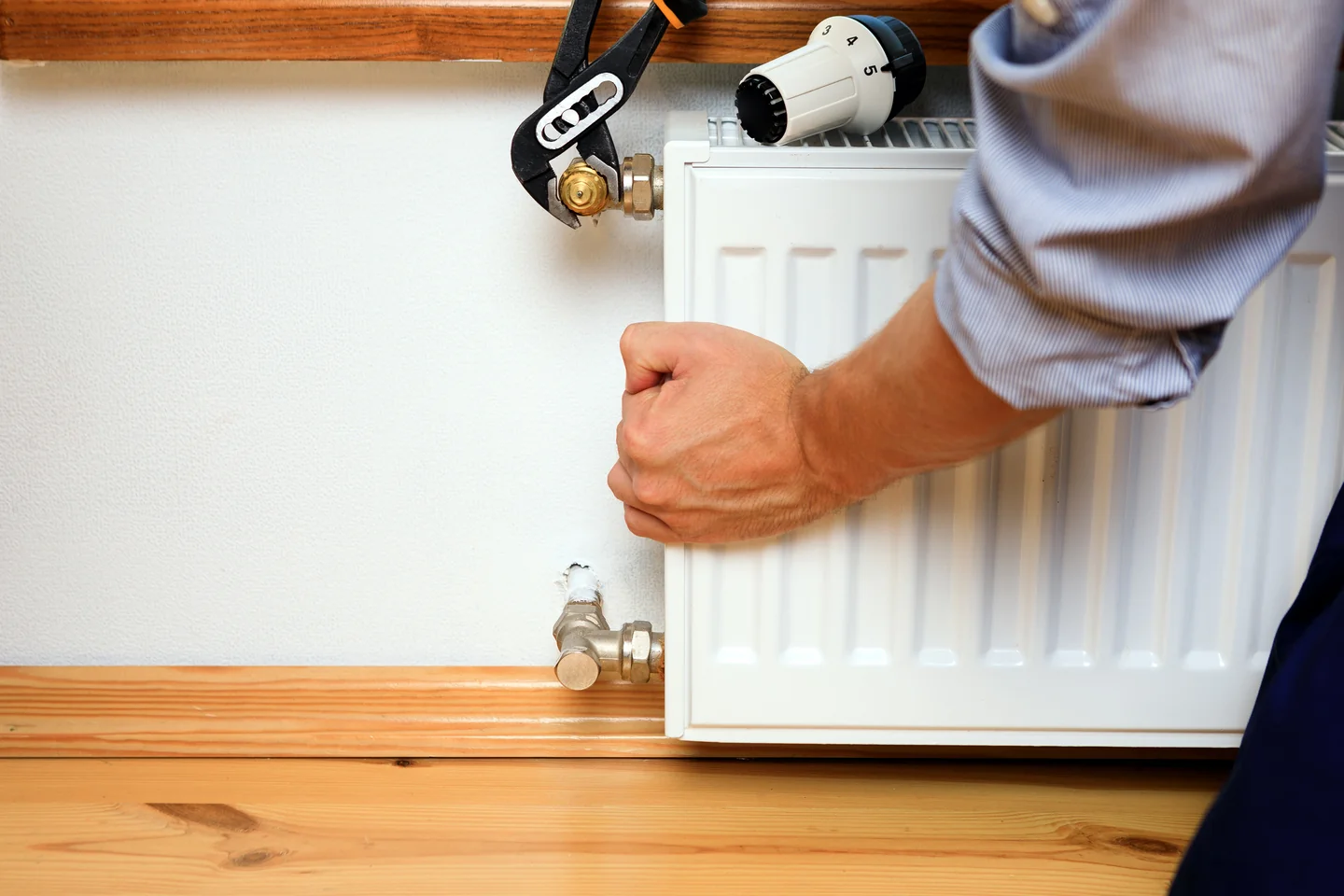 repair heating radiator close up man repairing radiator with wrench removing air from radiator